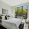 Bedroom with a bed, desk, and large windows